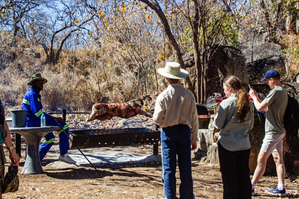 A group of students standing around a warthog on a spit in Matobo National Park